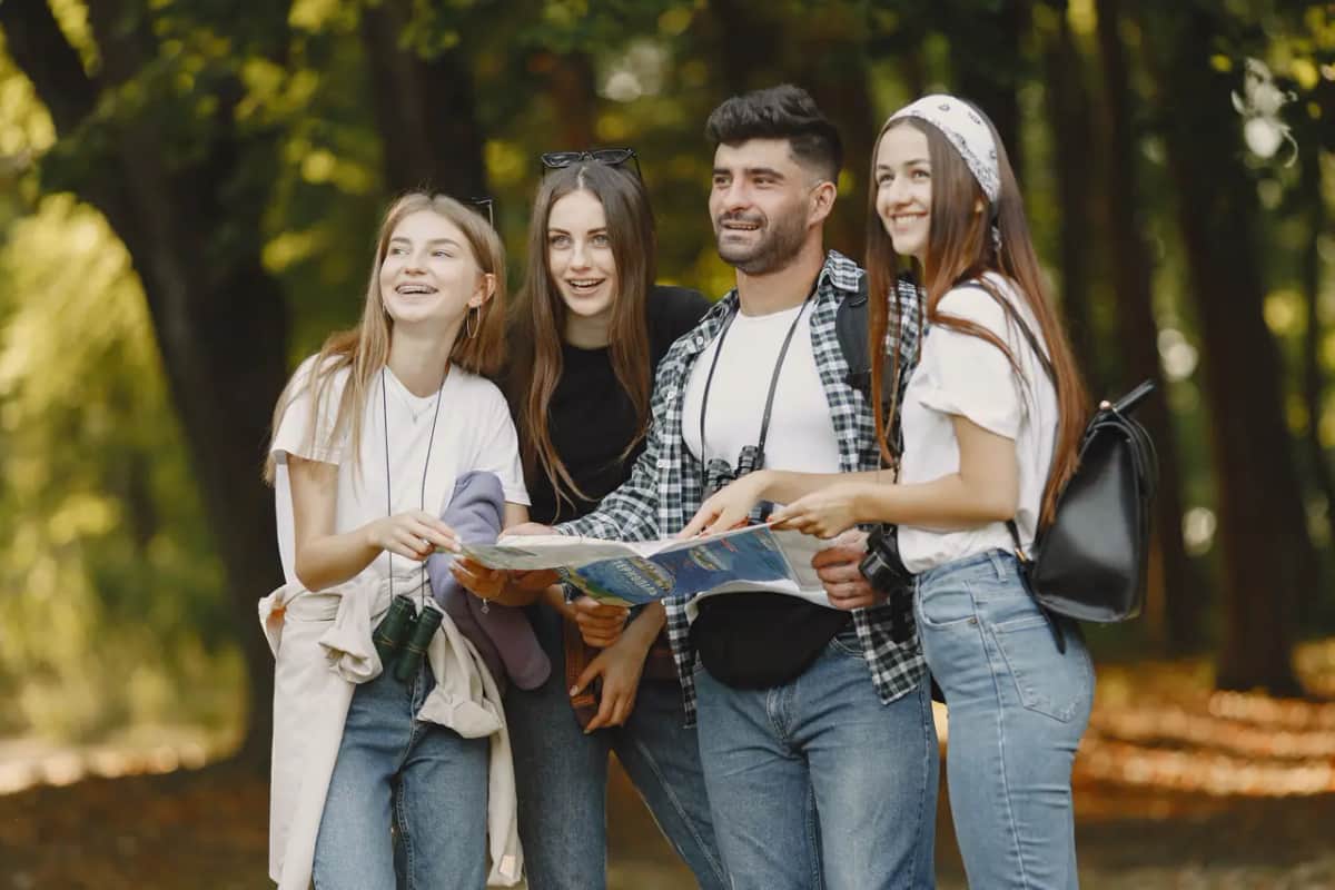 Компания друзей рассматривает карту во время прогулки по осеннему лесу