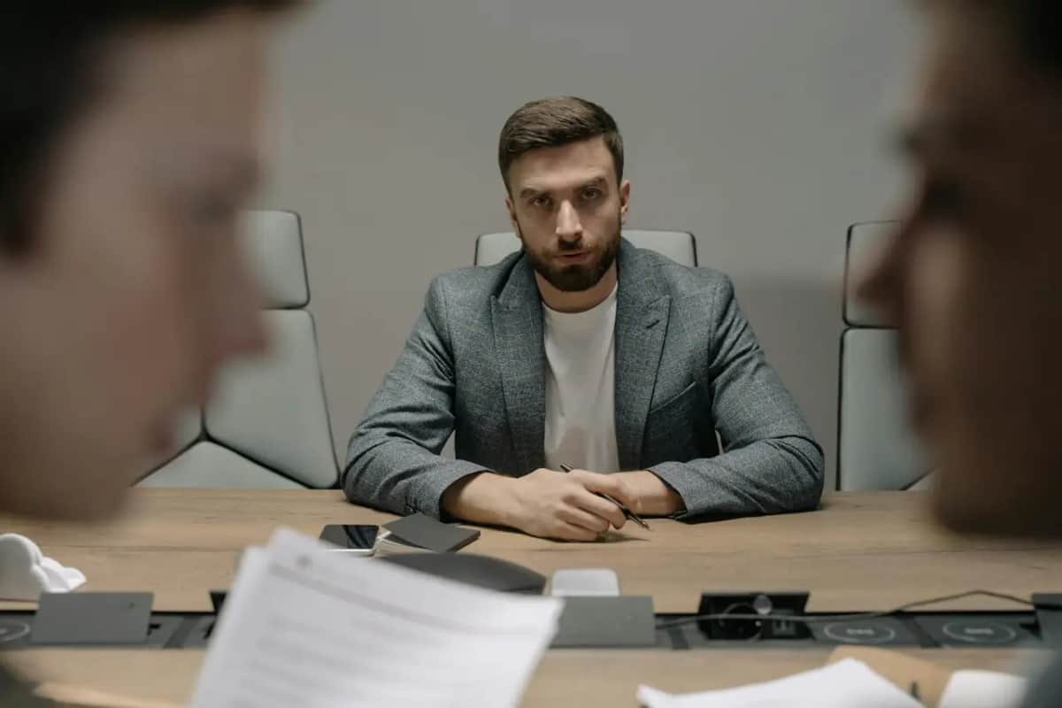Чоловік за столом переговорів дивиться співрозмовнику прямо в очі під час зустрічі