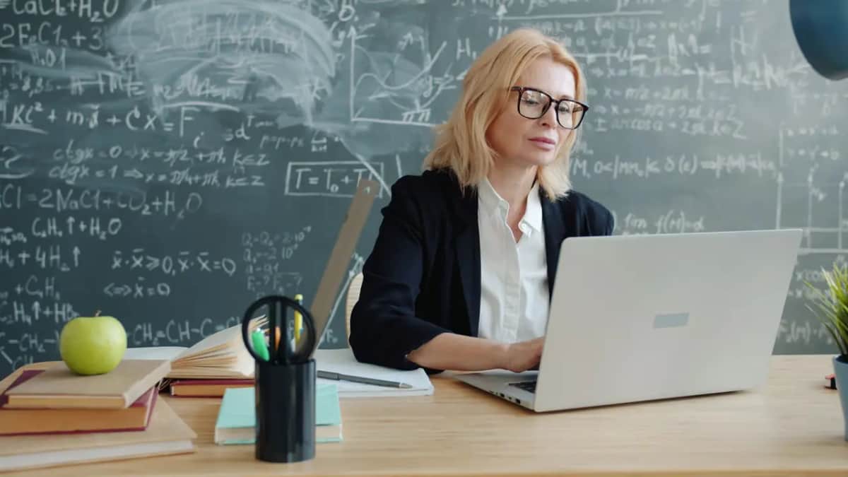 Учительница работает за ноутбуком в пустом классе после уроков