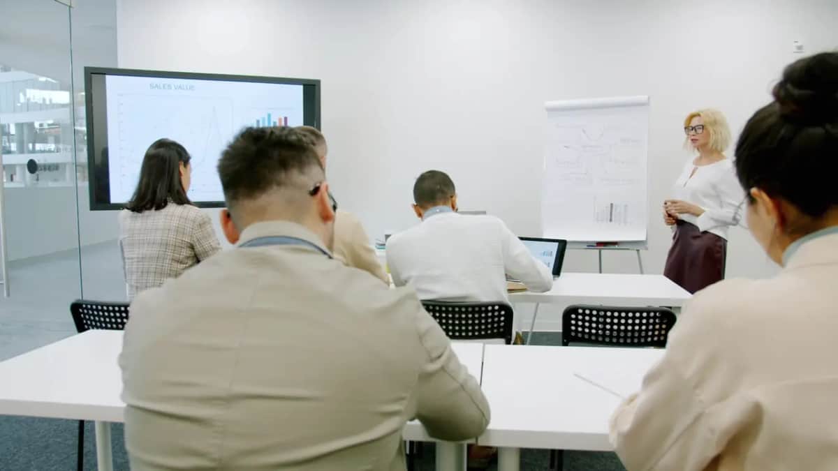 Група співробітників на корпоративному тренінгу: ведуча пояснює схему біля фліпчарта