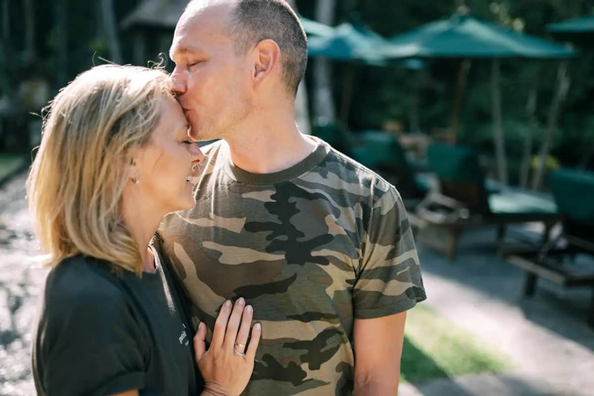 Чоловік у військовій футболці ніжно цілує дружину в чоло, стосунки в шлюбі під час війни і розлуки