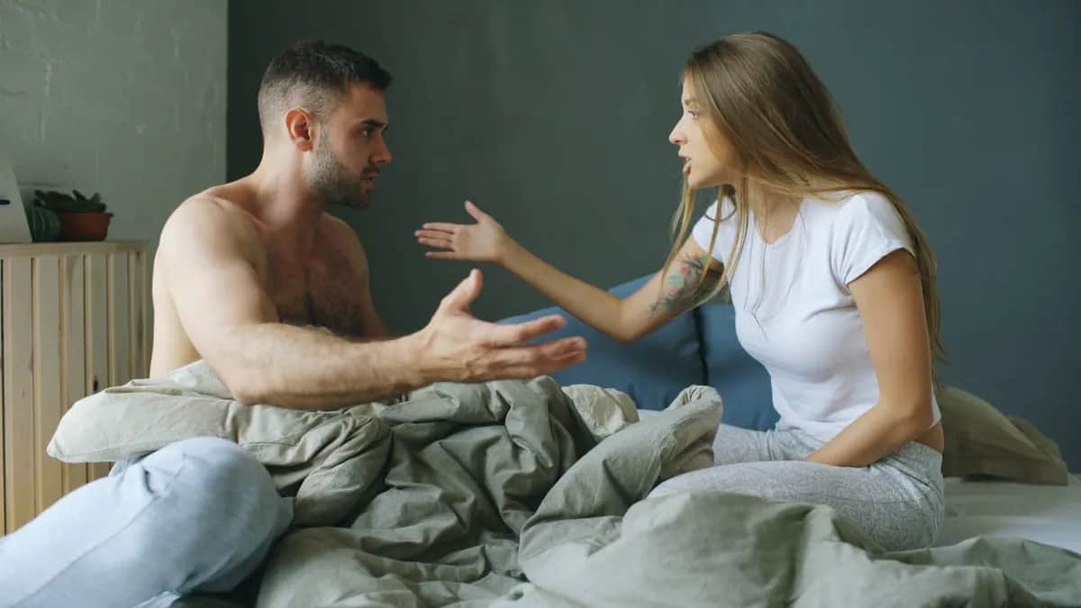 Пара сидить на ліжку й емоційно зʼясовує стосунки